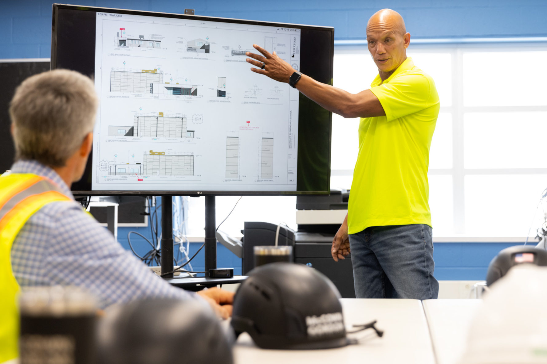 A McCownGordon Construction associate leading a meeting while pointing to drawings on a screen