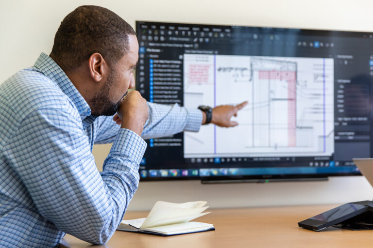 McCownGordon associate pointing at a construction estimate on a tv screen