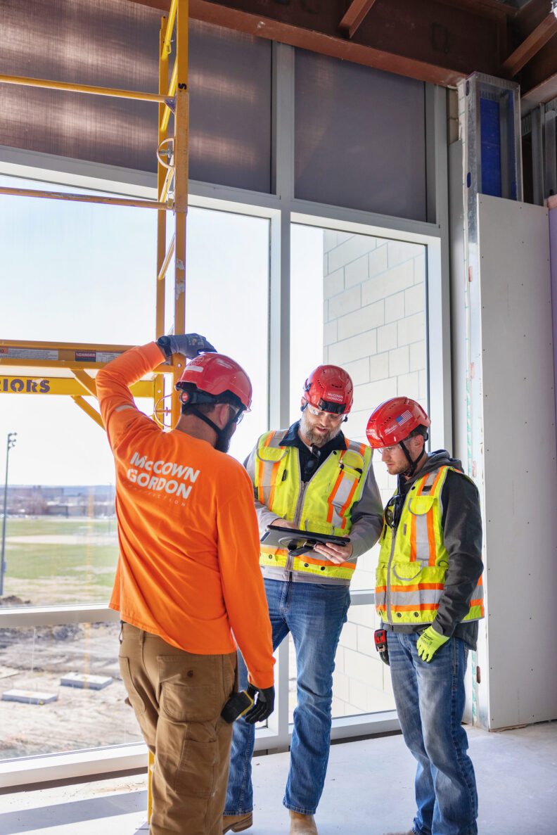 Three McCownGordon construction workers looking at plans on jobsite.
